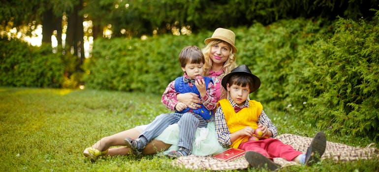 woman and two children sitting on green grass