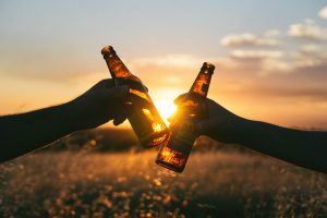 Close up of two hands holding beer bottles.