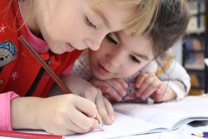 Two kids writing in notebook.