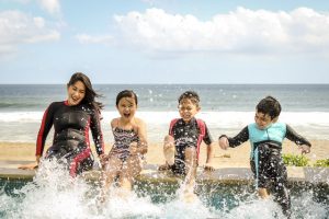 Mother with three kids playing at the beach.