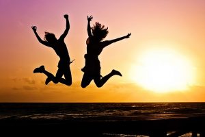 people jumping on the beach at sunset