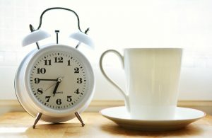 White clock next to a white mug.