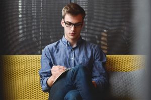 Young man siting and writing in his notebook.