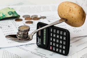 Spoon balancing on a calculator with coins and potato