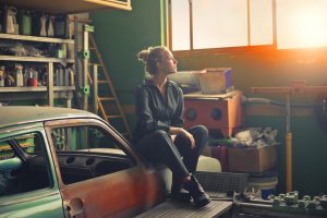 Packing your garage before you move- a girl sitting .on the car in the garage