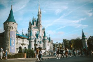 Castle at Disney World during the day with a large group of people walking in front of it; moving your family to Orlando can make this your standard weekend!