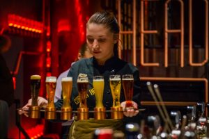 A waitress carefully carrying a rack of filled glasses