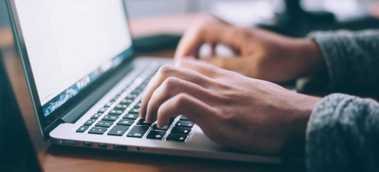 A group of people with their hands on desk planning a cost-benefit analysis next to a laptop.