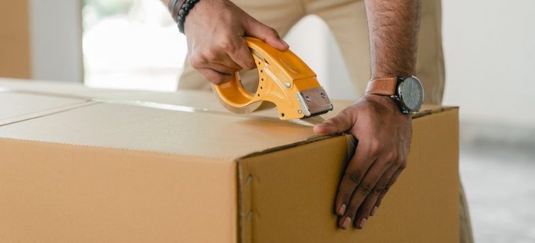 Man taping carrying box with scotch