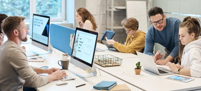 People in an office working on their laptops.