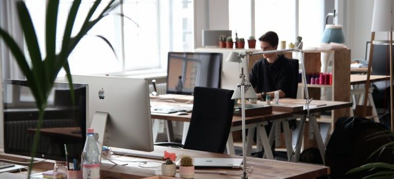 An office space with various desks and employees working on computers.