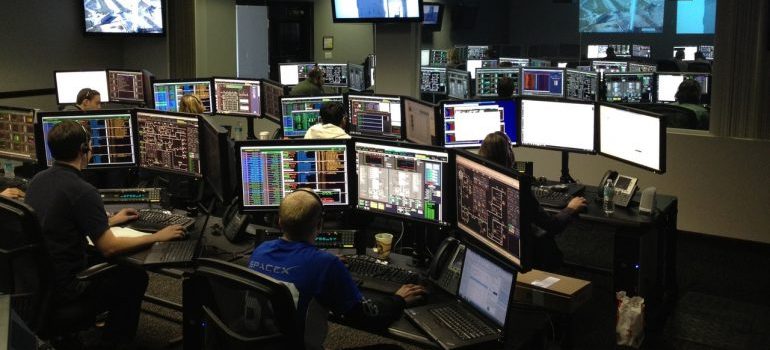 People working on multiple monitors in an office at night., before hiring commercial movers St Petersburg to relocate their offices.