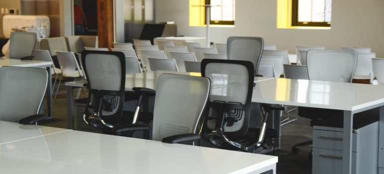 An empty office with white desks and chairs.