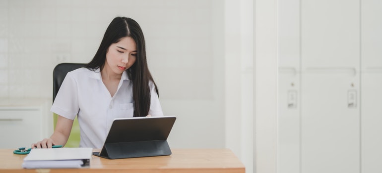 A woman browsing something on her tablet in an office space. 