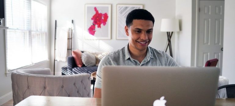 A smiling man working on his laptop.