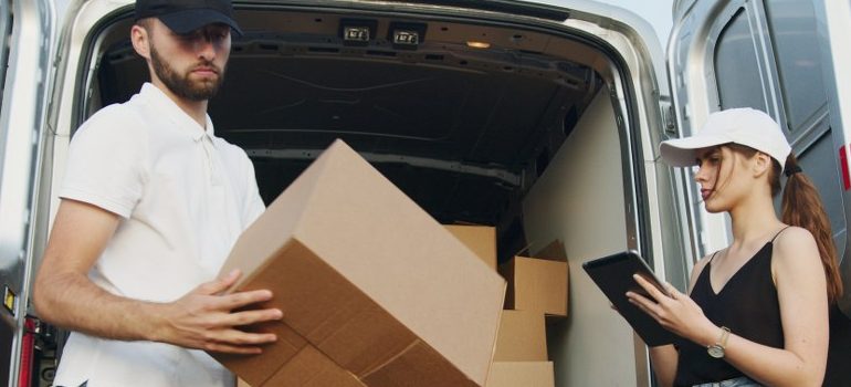 man unloading a moving truck, woman writing down