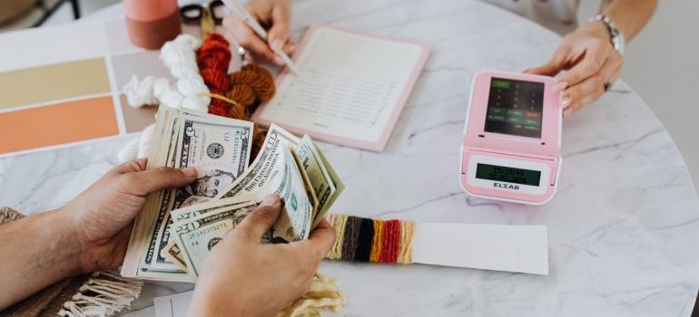 A person counting money while his partner uses the calculator.