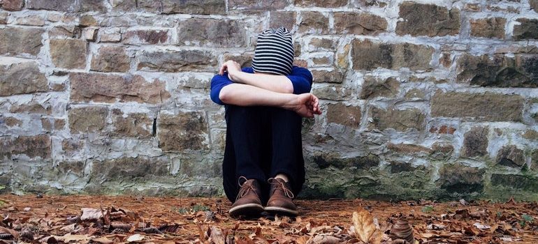 A woman holding her head in her knees.