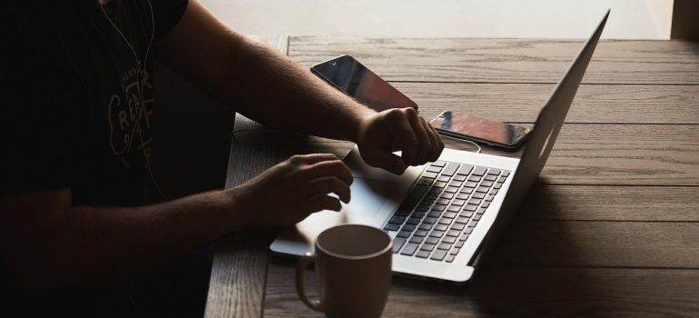 A person working on a laptop, searching for local movers Hallandale Beach. 