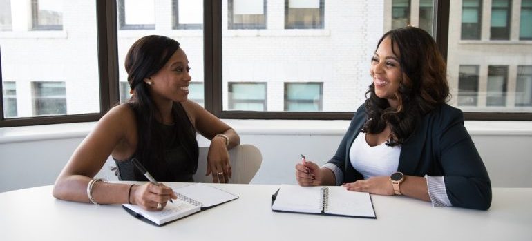 Smiling businesswomen writing in their notepads.