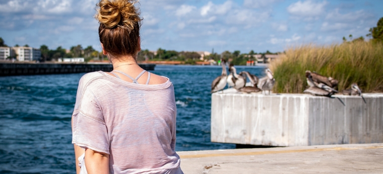 a woman sitting on a peer and waiting for the long distance movers Boynton Beach