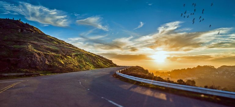 A windy road with hill and sunset in the background.