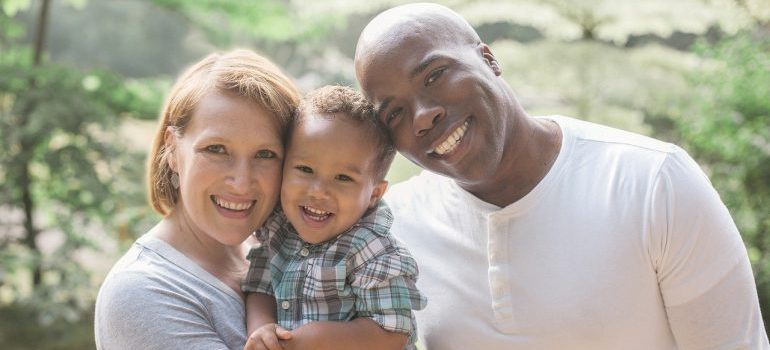 A family of three smiling and hugging.