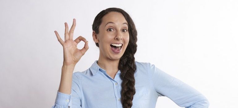 Woman holding a-ok sign, excited about upcoming relocation with local movers Aventura.