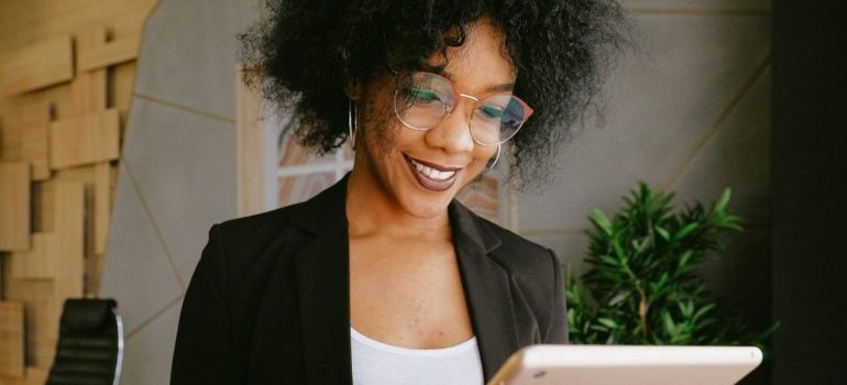 A smiling businesswoman researching commercial movers Largo FL on a tablet.