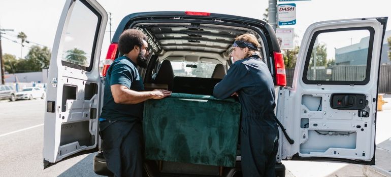 professional movers loading a sofa in the moving van