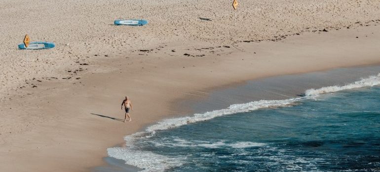 a man walking in swim shorts on beach