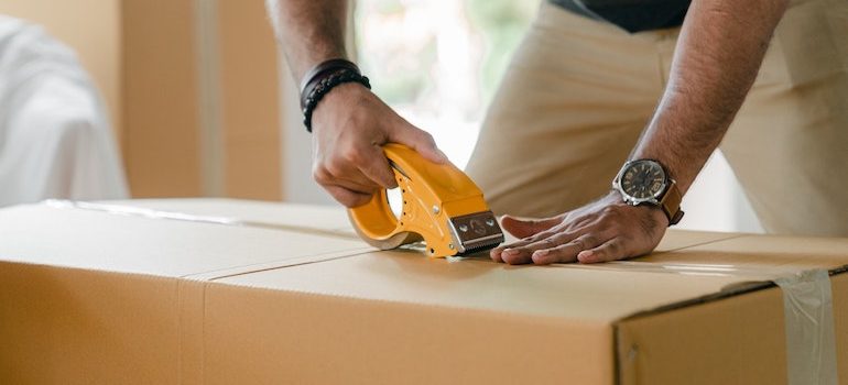 a man taping a box is part of local movers Ormond Beach