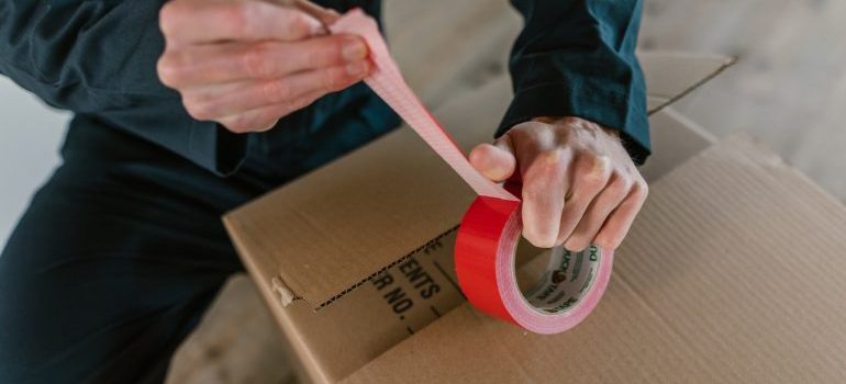 Packer sealing a cardboard box with a tape 