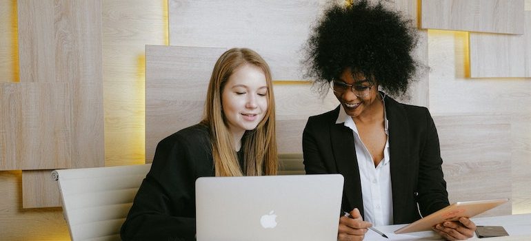 two women smiling and looking at computer 