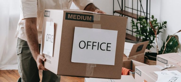 person carrying a cardboard box labelled 