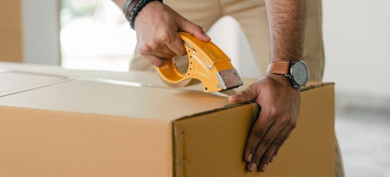 Man sealing moving box before Moving from Lake Worth to Fort Lauderdale