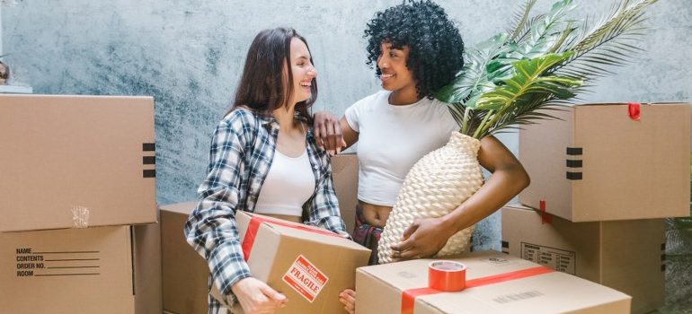 two women in the middle of moving boxes, smiling