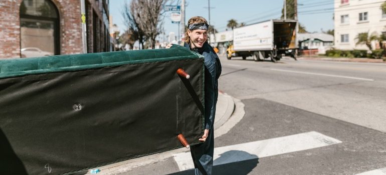 man on the street carrying a sofa