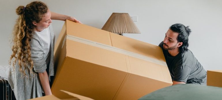 a couple lifting a cardboard box