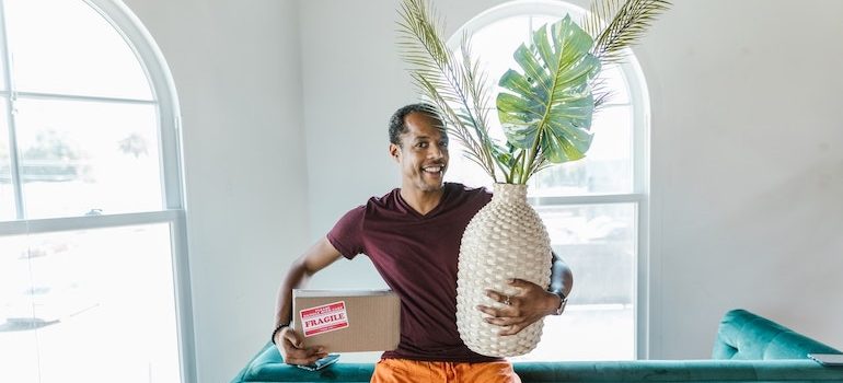 man holding a box and a vase with flowers