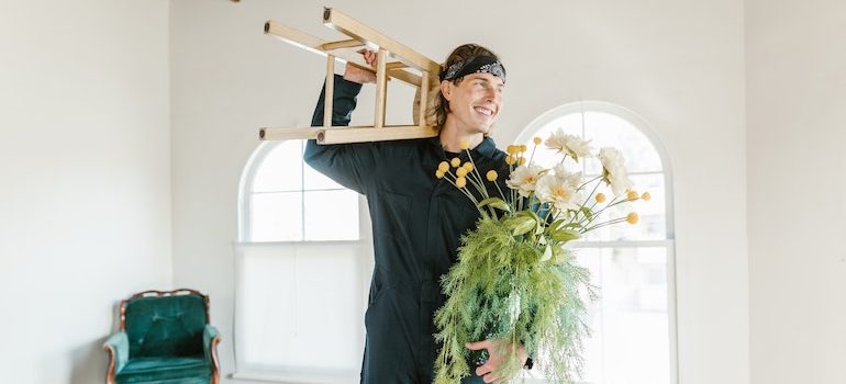 man holding a plant and a chair