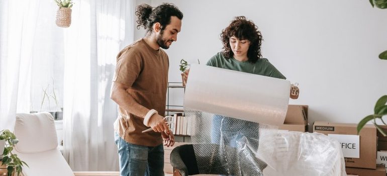 two people unrolling a sheet of bubble wrap