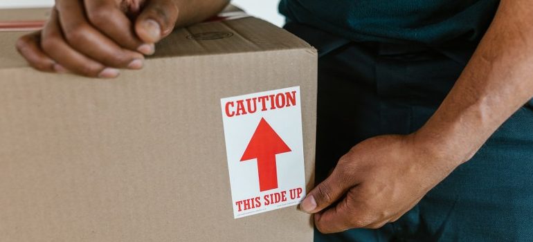 an employee of one of the best movers Panama City FL has, handling a cardboard box very carefully