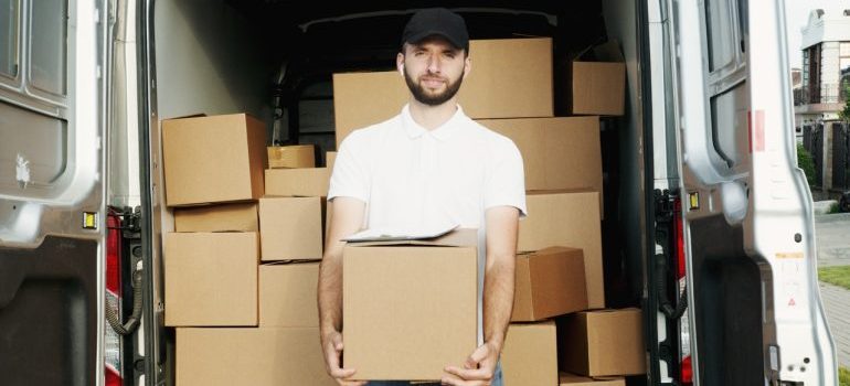 a man holding a box in front of the van