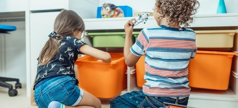 Two kids playing with toys in their room.