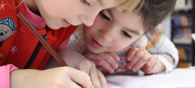 Two kids are learning how to write.