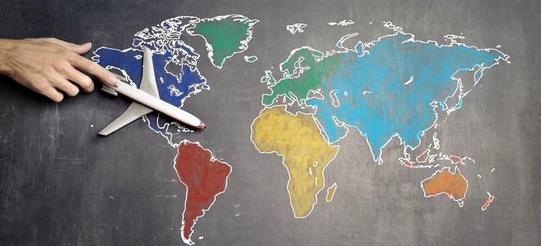 a hand pointing an airplane on a coloured world map