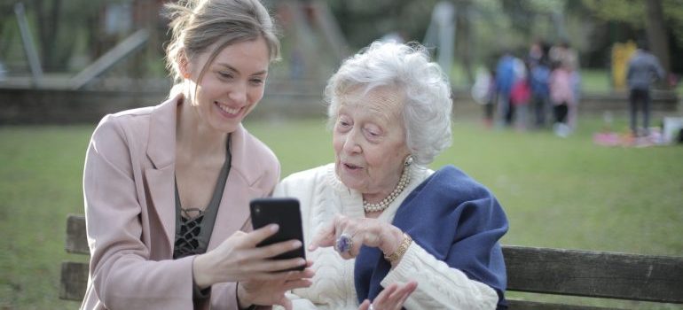 Daughter and her elder mother sitting in the park.