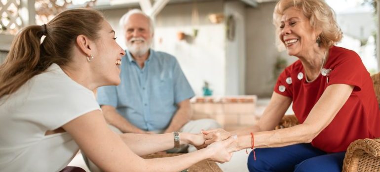 Elder parents and younger daughter holding hands and laughing.