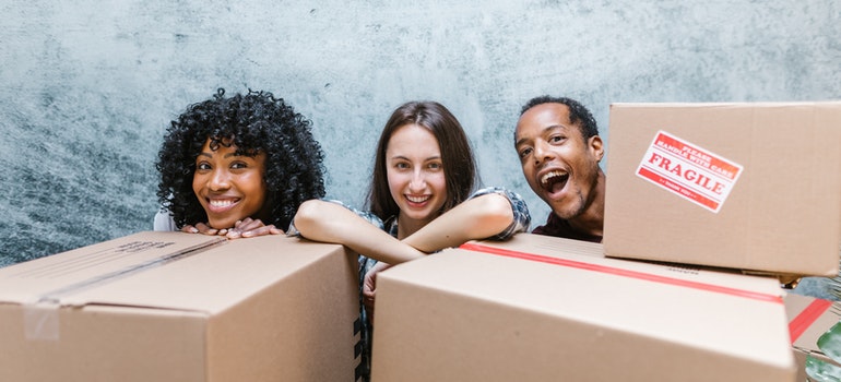 three people smiling while packing
